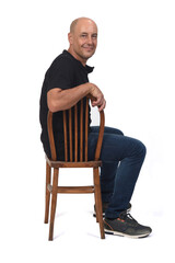 full portrait of a bald man sitting sideways on white background, looking at camera