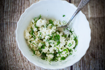 salted homemade cottage cheese with garlic and herbs in a bowl