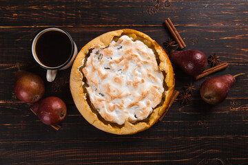 Pear pie with cream, homemade pastries on the wooden table, coffee and spices. Copy space.