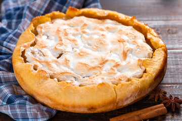 Pear pie with cream, homemade pastries on the wooden table, with spices. Copy space.