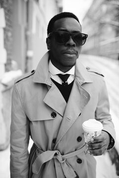 Stylish man walking down the winter street and drinking coffee on the go. Film styled black and white image. 