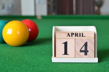 April 14, number cube with balls on snooker table, sport background.