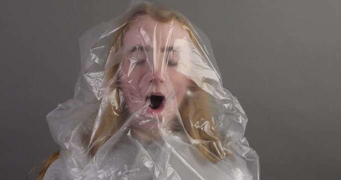 junge Frau mit Plastikt&uuml;te &uuml;ber dem Kopf versucht zu atmen