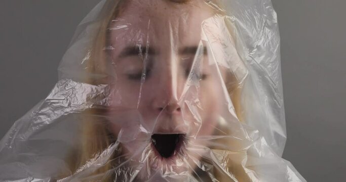 junge Frau mit Plastikt&uuml;te &uuml;ber dem Kopf versucht zu atmen