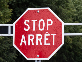 A bilingual English and French stop sign on a gate in Canada