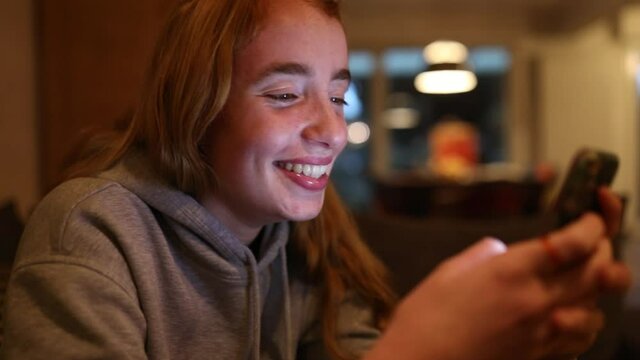 junge Frau freut sich nachts &uuml;ber Nachrichten auf ihrem Smartphone