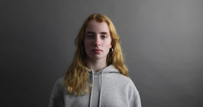 junge Frau blickt traurig und bl&auml;st eine Luftschlange Richtung Kamera