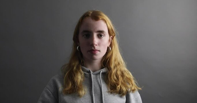 junge Frau blickt traurig und bl&auml;st eine Luftschlange Richtung Kamera