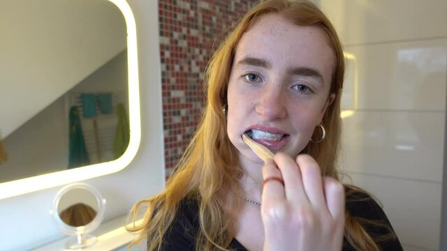 junge Frau putzt sich im Bad die Z&auml;hne