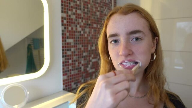 junge Frau putzt sich im Bad die Z&auml;hne