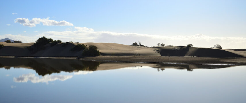 Dune landscape and blue sky reflected in the water, lagoon of Maspalomas, Gran Canaria, Spain