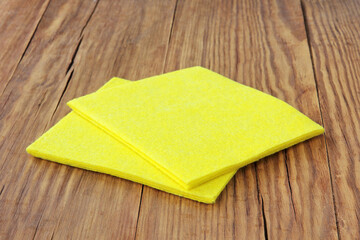 Pile of the yellow micro fiber napkins on wooden background. Household.