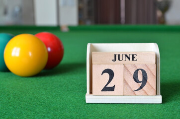 June 29, number cube with balls on snooker table, sport background.