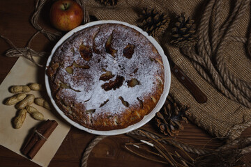 Homemade pie. Apple pie sprinkled with icing sugar. Pie on an autumn background. Autumn pastries
