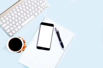 blue office desk background with smartphone with blank screen mockup, laptop computer, cup of coffee and supplies. Top view with copy space, flat lay.