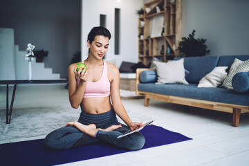 Content woman in lotus pose with apple and tablet