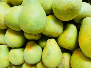 Close-up photo of pomelos in market. Group of fruits background.