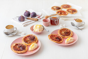 Homemade puff pastry fig tarts with vanilla and honey mascarpone - Gordon Ramsey recipe. White wooden table background.