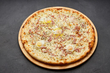 Delicious Italian Pizza Carbonara with Bacon, eggs and mozzarella cheese on dark background