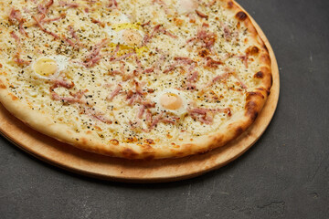 Delicious Italian Pizza Carbonara with Bacon, eggs and mozzarella cheese on dark background