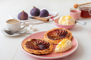 Homemade puff pastry fig tarts with vanilla and honey mascarpone - Gordon Ramsey recipe. White wooden table background.