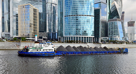 Fototapeta premium Barge with cargo floats along Moscow River past Moscow International Business Center (MIBC)