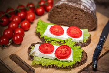 sandwich with cheese, lettuce and tomato on a wooden table