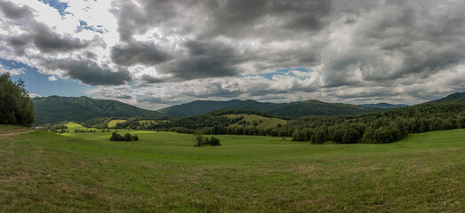 Panorama view with meadows and pasture land and gray clouds near Runina village