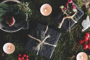 Yule (Christmas) themed flat lay of black gifts on nature forest background. Esoteric occult mood...