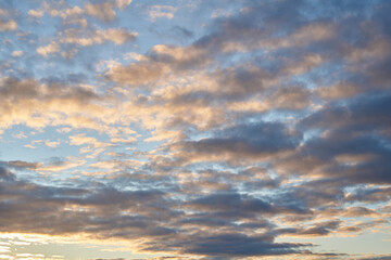 Beautiful evening blue sky at sunset with flaming bright light clouds. A warm summer evening at sunset.