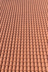 Solid background: roof covered with modern new orange tiles on a sunny day