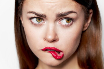 Close-up portrait of woman bites her lips red lipstick look