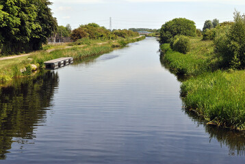 Fototapeta premium Landscape View along Still Waters of Canal in Summer Sunshine 
