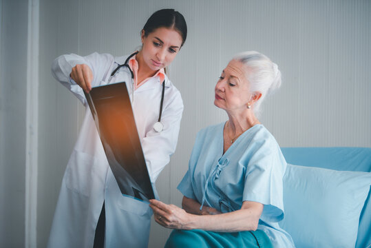 Woman doctor show x-ray film result and explain of health problem to elderly women patient at room in hospital. Healthcare homecare concept