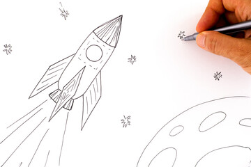 Woman hand with pen drawing picture with Rocket in space.