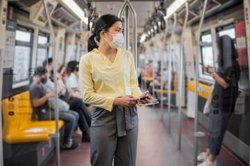 Woman wearing face mask on skytrain or subway train. Coronavirus (COVID-19) outbreak prevention in public transportation.