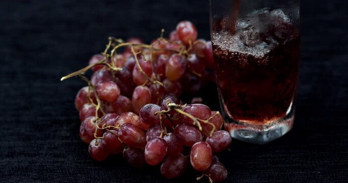 close up ripe grape fruits, next a bottle with ice cubes and grape juice poured into it
