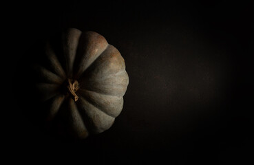 pumpkin in moody style, soft light with shadow on black background, mystical and dramatic scene, ideal for graphic backgrounds with text space, top view