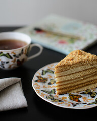 a piece of honey cake on a saucer and a Cup of tea with butterflies