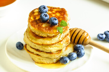 Fritters, pancakes close-up on a white plate. Honey, blueberries. Selective focus