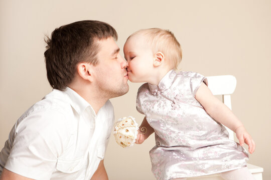 happy family. dad kisses little daughter. baby girl with short hair. children's holiday, birthday. fatherly love.
