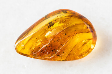 closeup of sample of natural mineral from geological collection - polished Amber gem stone on white marble background from Baltic Sea, Kaliningrad, Russia