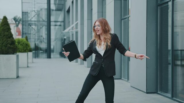 Happy business woman in a business suit look around starting dancing near the office building. Entrepreneur victory winner. Corporate successful. Cheerful happiness.