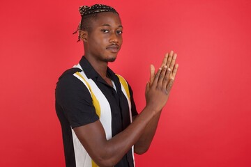 African american man with braids wearing casual shirt over isolated red background clapping and...