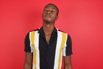 African american man with braids wearing casual shirt over isolated red background looking sleepy and tired, exhausted for fatigue and hangover, lazy eyes in the morning.