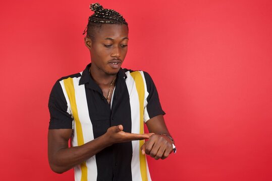 African american man with braids wearing casual shirt over isolated red background In hurry pointing to watch time, impatience, upset and angry for deadline delay.