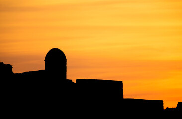 Obraz premium Silhouette of watch tower of ancient Bahrain Fort during sunset, Bahrain