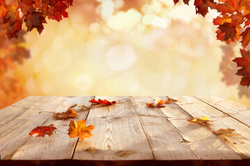 Naklejka na ściany i meble Sunlight in autumn forest. Beautiful landscape with yellow trees and sun. Colorful foliage on wooden table. Falling leaves natural background.