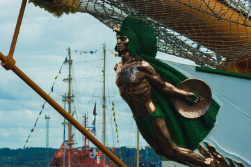 Figurehead of a boat in the shape of a green and gold Indian with a shield in his hand