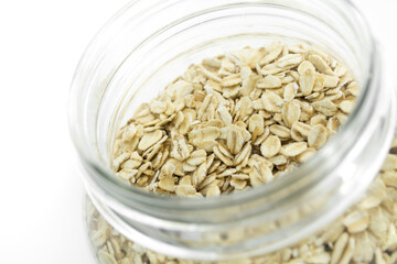 Glass jar full of natural oats, isolated on white background.